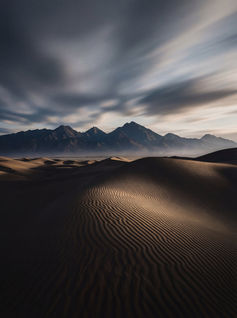 Generative art print of wind-sculpted sand dunes at twilight, ripple patterns leading to dark mountains, framed in matte black solid wood.